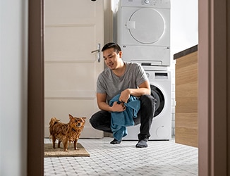 Ein Mann mit Handtuch hockt vor einem nassen Hund.