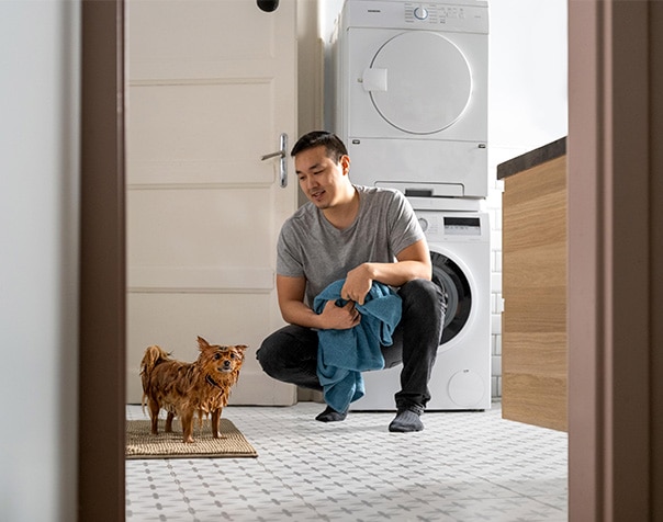 Ein Mann mit Handtuch hockt vor einem nassen Hund.